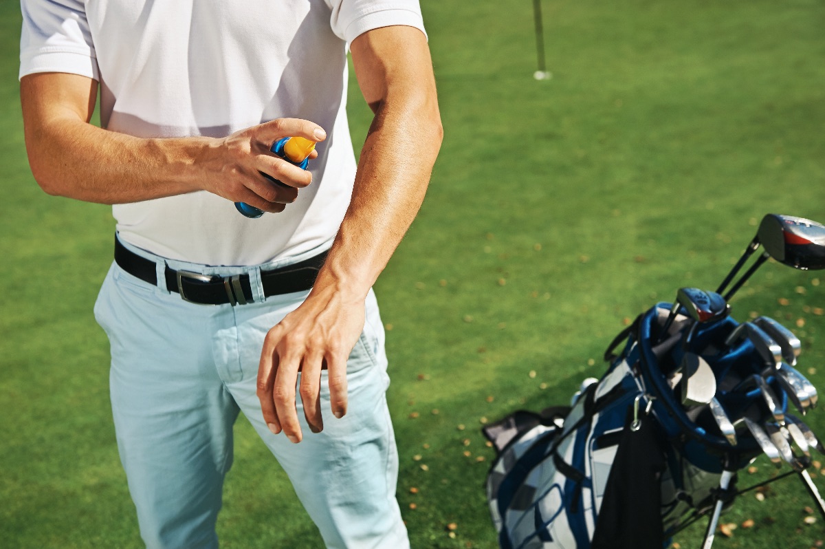 Golfer putting on sunblock